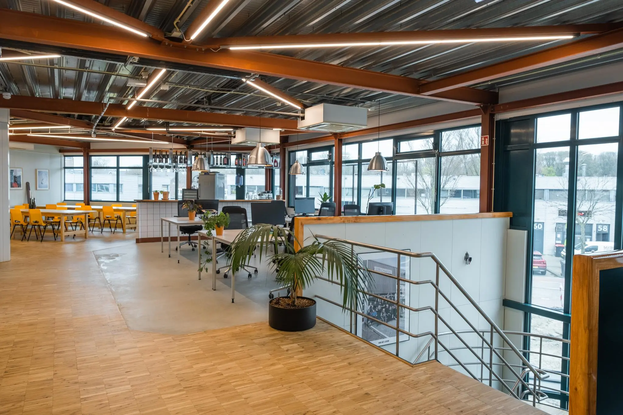 Moderne kantoorruimte aan de Johan van Hasseltweg met open werkplekken, gele eetkamerstoelen en grote ramen voor natuurlijk licht.